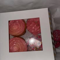 Boxed pink rose-swirled cupcakes with sprinkles